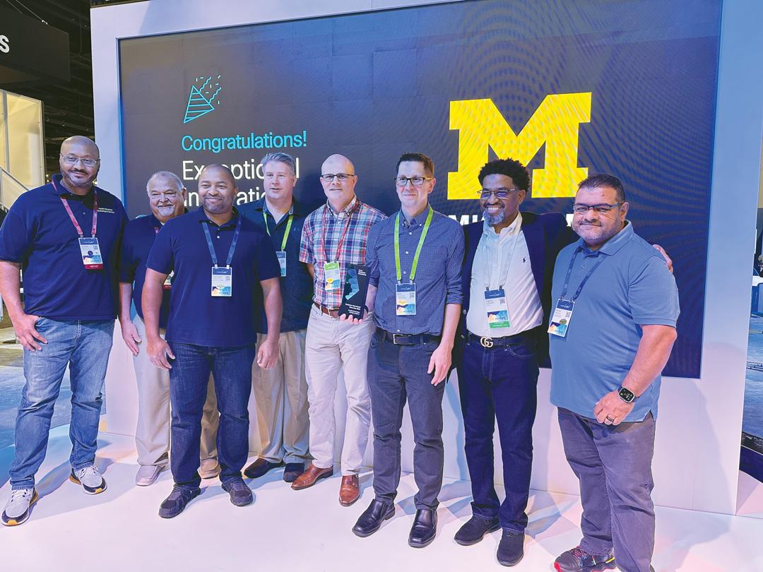 Group of people posing in front of screen with Michigan Medicine logo